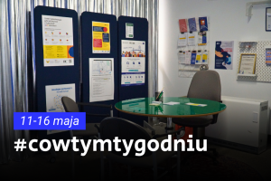 Przestrzeń biurowa z tablicami informacyjnymi i ulotkami na ścianach. Z przodu znajduje się okrągły stół i krzesła, a na obrazie widnieje napis „#cowtymtygodniu 11–16 maja”.